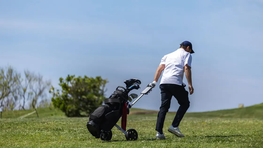 Golfare drar golfvagn på banan