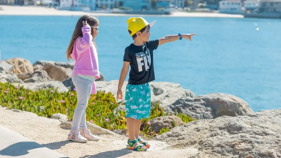 Barnfötter i sandaler på stranden